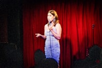 a woman in a blue dress standing in front of a red curtain