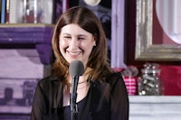 a woman is smiling while holding a microphone